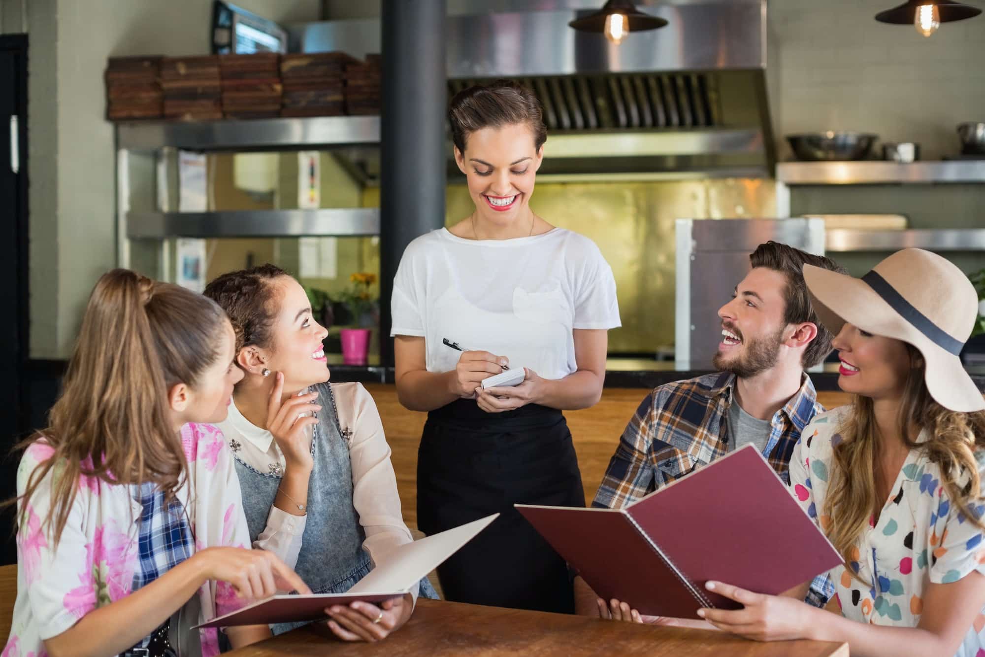 Waitress writing orders of customers in restaurant